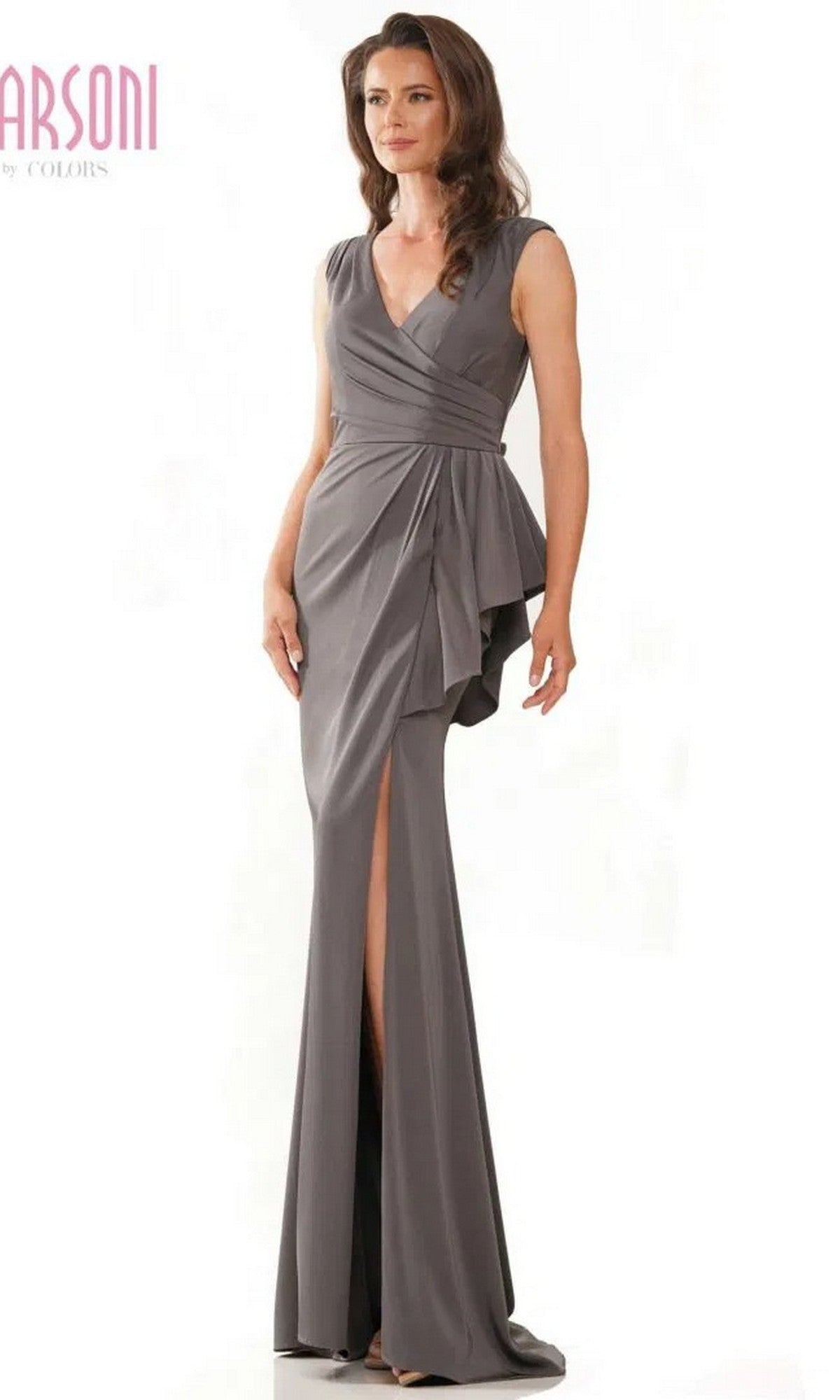 A woman wearing the Marsoni MV1227, a charcoal long formal dress with a sleeveless V-neck, wrap ruched bodice, draped waist detail, and side slit, stands against a plain white background.